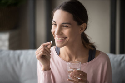 woman taking medication while smiling